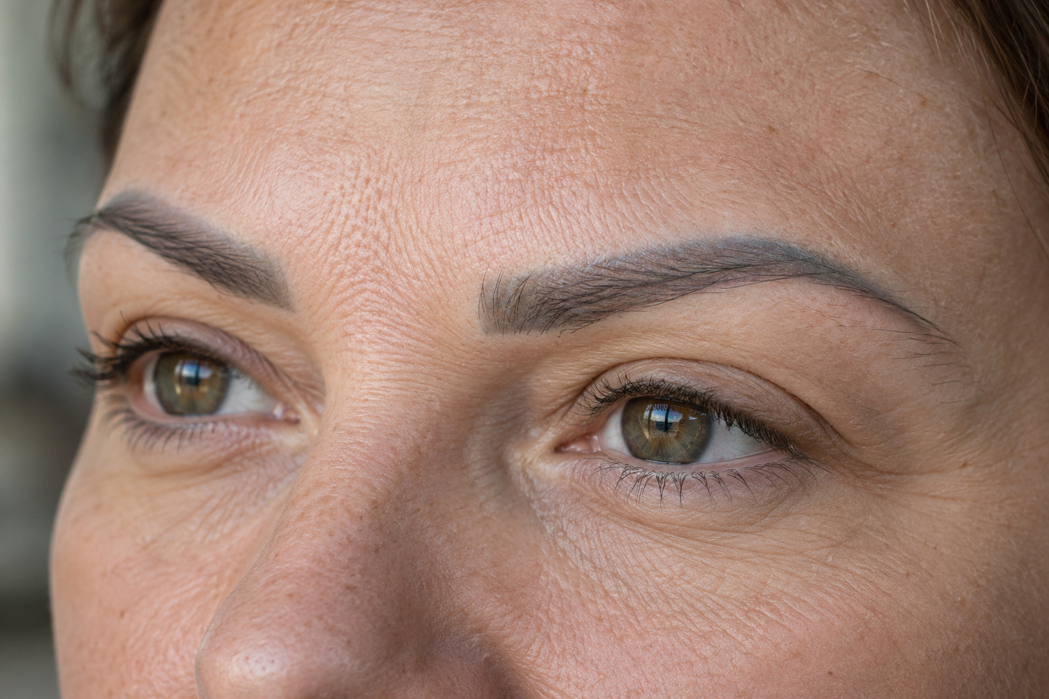 Close view of a healed eyebrow tattoo with a muted grey cast.